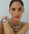 Model on light blue backdrop wears Claude Necklace, Laguna Necklace and Arc Cuff