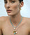 Model on sky blue backdrop wears two tiny bead necklaces with semiprecious charms.