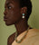 Model on green backdrop wears Yellow Sapphire Necklace and 14k Gold, Turquoise & Freshwater Pearl Earrings. 