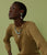 Model on green backdrop wears mustard knit top with Alvar Earrings and Vizcaya Necklace.