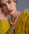 Model on grey backdrop wears yellow feather sweater with Pacifica Pearl Necklace and Porto Medallion