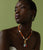 Model on green backdrop wears Mood Necklace in Red Aventurine with assorted mood charms.
