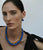 Model on grey backdrop wears black top with Mood Necklace in Gold and blue Laguna Necklace.