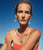 Model against blue sky wears coral tube top with Algarve Earrings in Turquoise and assorted necklaces.