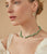 Model on tan backdrop wears cream top with Turquoise, Pearl, Diamond & 14k Gold Necklace. 