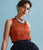 Model on blue backdrop wear orange pleated top, black skirt with Catalonia Necklace and Ethereal Pool Earrings.
