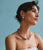 Model on blue backdrop wears strappy dress with Pablo Earrings in Rose and Pink Cliffs Necklace.