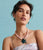 Model on grey backdrop wears strappy dress with Vinca Flower Necklace in Tea Rose and Tile Earrings.