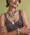 Model on green backdrop wears brown feather top with Gemma Earrings and Necklace, Rock Candy and Two of Hearts Necklaces
