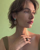 Video of model posing on green backdrop, wearing Monument Ring in Sandstone and Sandstone Earrings.