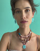 Video of model on blue backdrop in floral dress, with assorted jewelry including New Bloom Earrings in Cerulean.