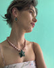 Video of model on grey backdrop in strappy dress with Vinca Flower Necklace in Tea Rose and Tile Earrings.