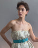 Video of model posing on grey backdrop in strapless floral dress with Louise Belt in Teal Suede and Organic Hoops.