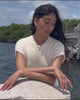 Video of model leaning against rock, wearing white ribbed dress, Crystal Column Earrings and Pearl Pyramid Necklace.