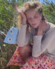 Video of model sitting in grass, holding up Gala Bag in Blue Daisy.