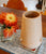 Bowl Bottom in Tangerine Ice sits beside orange flower bouquet atop printed blue and white fabric, on wooden dining table.