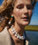 Model with water in background wears beige knit with Demy II Earrings and Monte Palace Necklace.