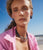 Model on beach in pink shirt wears Camilo Stud Earrings and Santo Necklace in Rose and Sea.