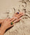 Model's hands in sand wear Monument rings on both hands in Jade, Ochre, Terra and Azure.